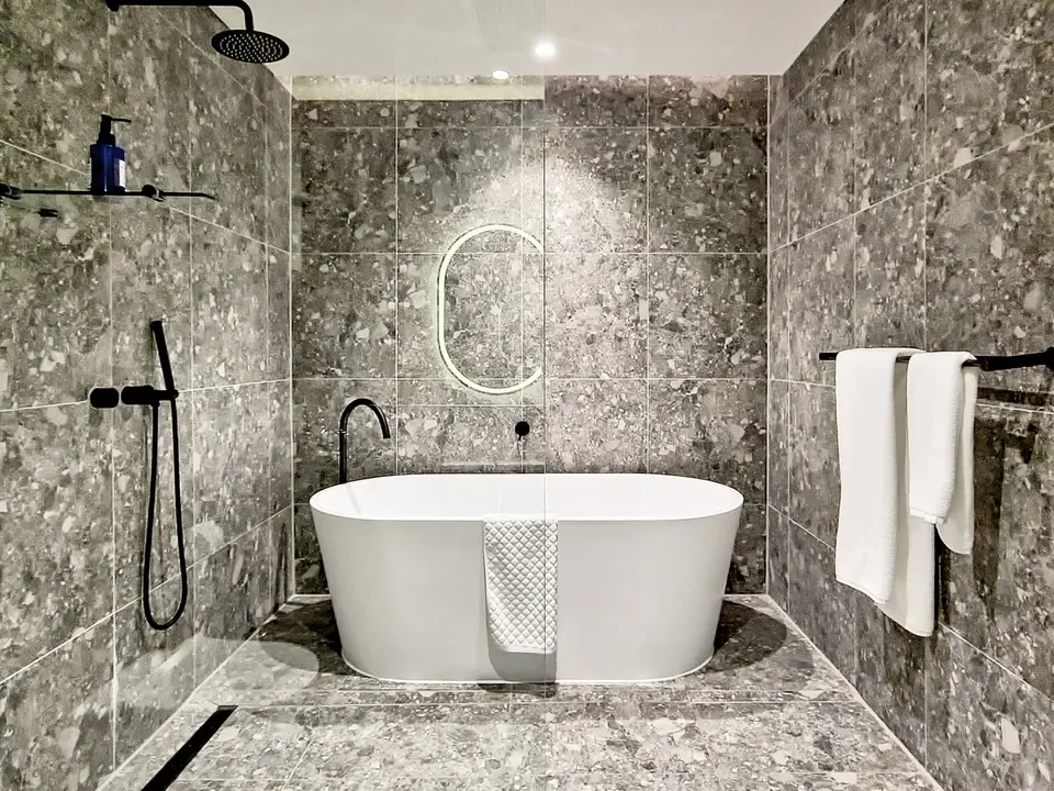 Penthouse bathroom at The Rockefeller with terrazzo-look porcelain, a freestanding bath and matt black fittings