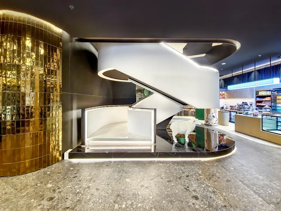 The lobby of The Rockefeller with a sculptural white stair and gold tiled wall